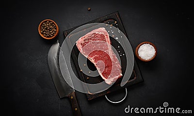 Fresh raw piece of beef meat, striploin steak on a black background, top view. Marbled piece of meat New York Stock Photo