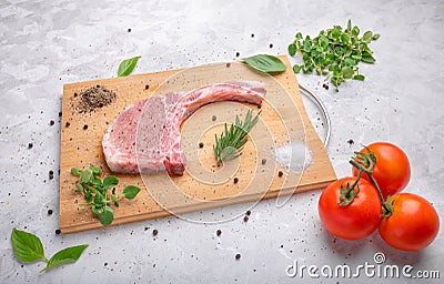 Fresh raw pork with spices and rosemary, oregano and black pepper on wooden slate, on white marble background, pork chop on a bone Stock Photo