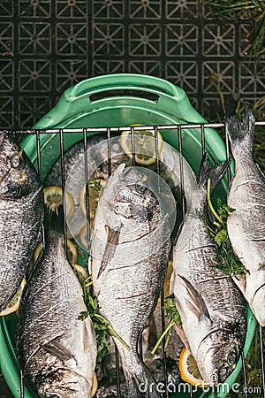 Fresh and raw stuffed fish with lemon and parsley on the grid Barbeque in the garden in summer ready and wait for the Stock Photo