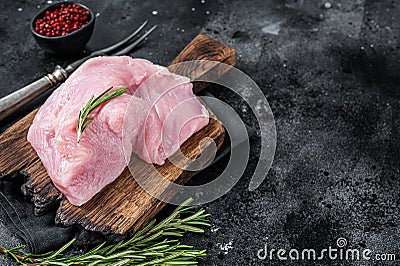 Fresh Raw whole big turkey breast fillet on wooden board. Black background. Top View. Copy space Stock Photo