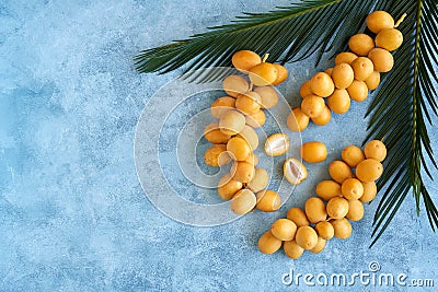 Fresh raw yellow dates with palm leaf on blue background. Top view Stock Photo