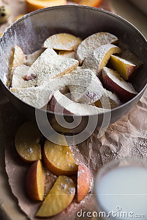 Fresh red apple slices sprinkled with flour in a stylish iron dish lying on a white window sill. A glass of milk are Stock Photo