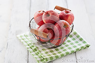 Fresh red juicy apples in a basket on a green textile on a wooden background Stock Photo