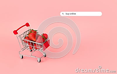 Fresh strawberry in shopping card on pink background. Online shopping and Valentines Day minimalistic concept. Stock Photo