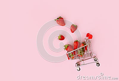 Fresh strawberry in shopping cart on pink background. Online shopping and Valentines Day minimalistic concept. Stock Photo