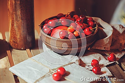 Fresh ripe cherries on plate with wrapped gift on wooden table Stock Photo