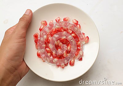 fresh ripe juicy grains Pomegranate, (Punica granatum) seeds in the white dish in hand woman Stock Photo