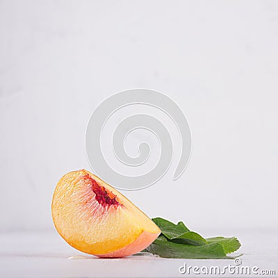 Fresh ripe juicy piece peach and green leaf on white wood board, square. Stock Photo