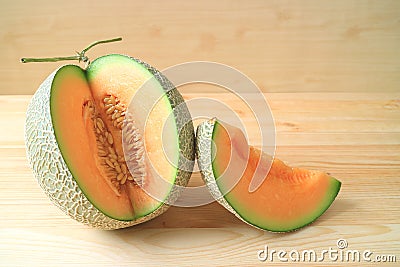 Fresh ripe muskmelon whole fruit with a piece of sliced fruit on a wooden table Stock Photo