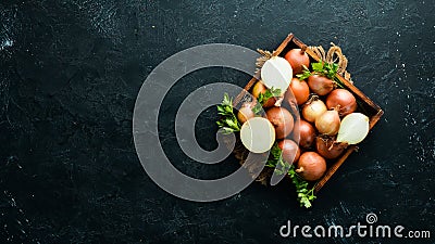 Fresh ripe onions in wooden box on black background. Top view. Stock Photo