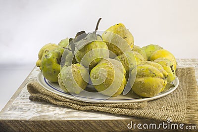 Fresh ripe organic quince with leaves on grey wooden table and rough linen Vinrage still life Stock Photo