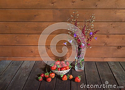 Fresh ripe strawberry and bouquet made of red astilbe and blue bell flowers on wooden table. View with copy space Stock Photo
