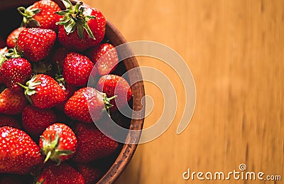 Fresh ripe strawberry in the clay bowl on the red cloth table. Stock Photo