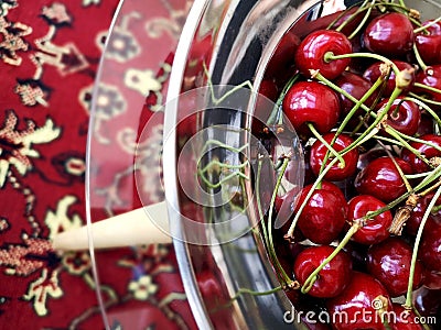 Sweet ripe cherries in a metal plate on a glass table. Stock Photo