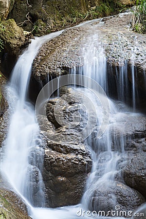 Fresh river water flows from a small waterfall that form two rocks Stock Photo