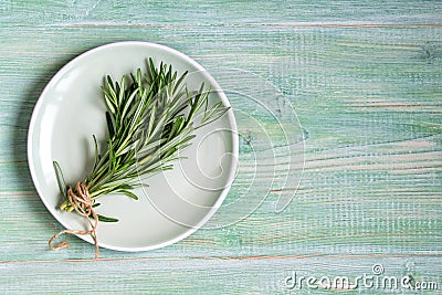 Fresh rosemary bunch on a plate on green wooden background, top view Stock Photo