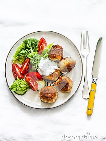 Fresh salad and canned tuna potato fish balls with greek yogurt cilantro sauce on light background, top view Stock Photo