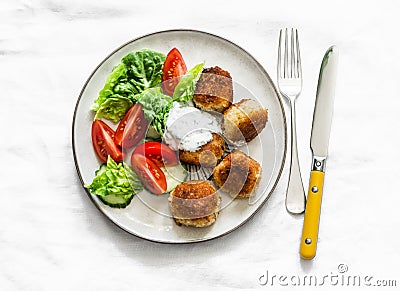 Fresh salad and canned tuna potato fish balls with greek yogurt cilantro sauce on light background, top view Stock Photo