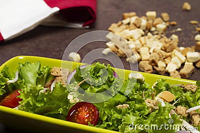 Fresh salad of tomato lettuce and onion with red striped cloth, bread laces and wooden spoon Stock Photo