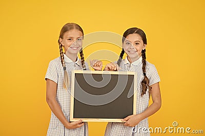 Fresh school information copy space. School news. True information. Little girls hold writing surface yellow background Stock Photo