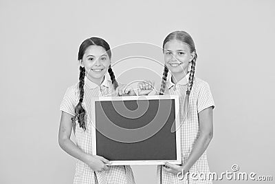 Fresh school information copy space. School news. True information. Little girls hold writing surface yellow background Stock Photo