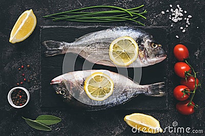 Fresh fish with spices, vegetables and herbs on slate background ready for cooking Stock Photo