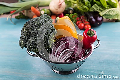 Fresh seasonal vegetables in colander on wooden table background Stock Photo