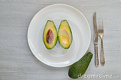 Fresh sliced avocados on the white plate. Healthy vegetarian diet food on gray background Stock Photo