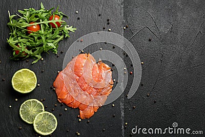 Fresh sliced salmon fillet with arugula and lemon on slate plate, top view Stock Photo