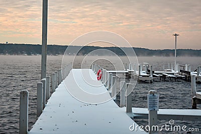 Snow Covered Dock With Lifebuoy Mist rising from the Lake Stock Photo
