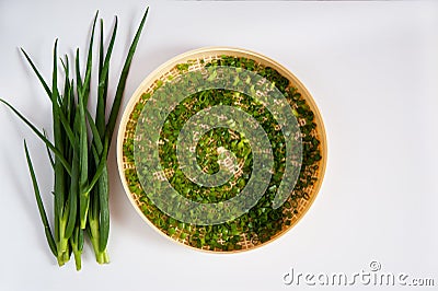 Fresh spicy spring green onion feathers are cut and placed on a dehydrator grid on a white background. Stock Photo