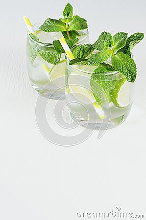 Fresh spring drink with slices lime, twig mint, ice, bubbled water, straw on soft blue wood plank, top view, copy space. Stock Photo