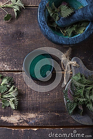 Fresh stinging nettle leaves on wooden table.Urtica dioica oil with spirulina powder, a healthy supplement to improve health Stock Photo