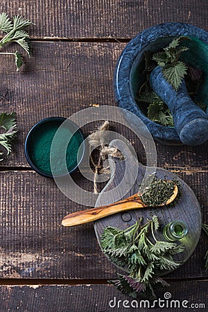 Fresh stinging nettle leaves on wooden table.Urtica dioica oil with spirulina powder, a healthy supplement to improve health Stock Photo