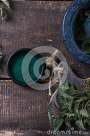 Fresh stinging nettle leaves on wooden table.Urtica dioica oil with spirulina powder, a healthy supplement to improve health Stock Photo