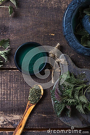 Fresh stinging nettle leaves on wooden table.Urtica dioica oil with spirulina powder, a healthy supplement to improve health Stock Photo