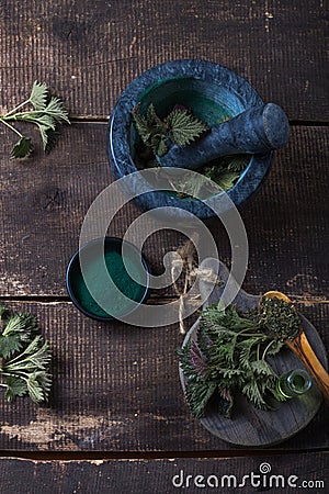 Fresh stinging nettle leaves on wooden table.Urtica dioica oil with spirulina powder, a healthy supplement to improve health Stock Photo
