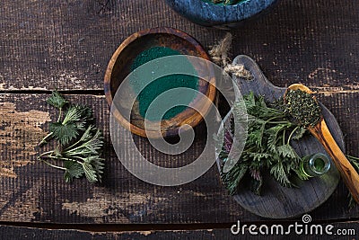 Fresh stinging nettle leaves on wooden table.Urtica dioica oil with spirulina powder, a healthy supplement to improve health Stock Photo