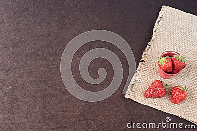 Fresh strawberries in mini metal bucket on hessian jute. Black background. Stock Photo