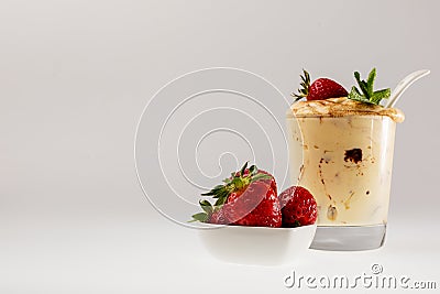 Fresh strawberries in a white saucer and tiramisu in a glass glass on a white background Stock Photo