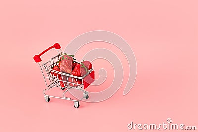 Fresh strawberry in shopping card on pink background. Online shopping and Valentines Day minimalistic concept. Stock Photo