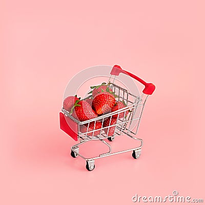 Fresh strawberry in shopping card on pink background. Online shopping and Valentines Day minimalistic concept. Stock Photo