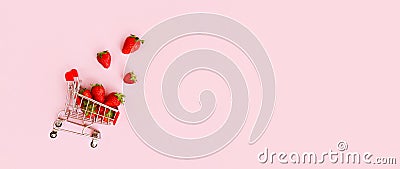 Fresh strawberry in shopping cart on pink background. Online shopping and Valentines Day minimalistic concept. Stock Photo