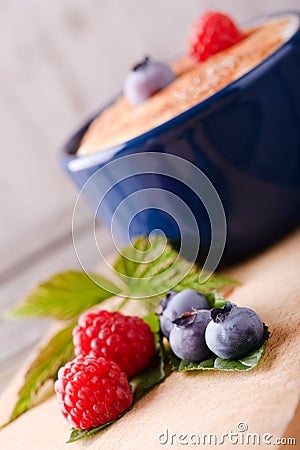 Fresh summer berries in front of dessert in blue bowl Stock Photo