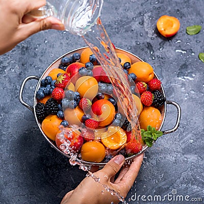 Fresh summer fruits and berries, apricots, blueberries, strawberries in colander, washing fruits and berries, woman`s hands, wate Stock Photo