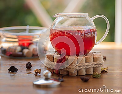 Fresh sweet red tea with berries and dried leaves. A full teapot on a decorative stand blurred outside cafe background. Stock Photo