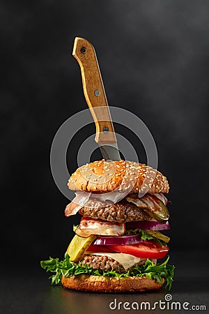 Fresh tasty burger with knife on a black background Stock Photo