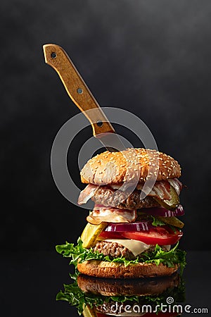 Fresh tasty burger with knife on a black reflective background Stock Photo