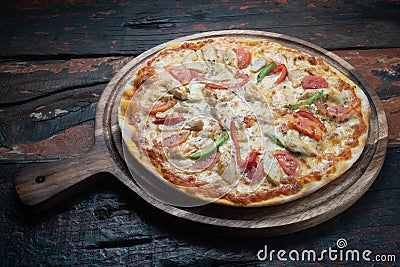 Fresh tasty pizza with chicken, tomato, paprika and mozzarella cheese on rustic wooden background Stock Photo