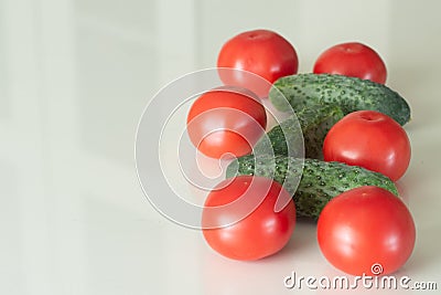 Fresh tomatoes and cucumber on a white glass kitchen table. Fresh organic food ingredients. Top view. Stock Photo